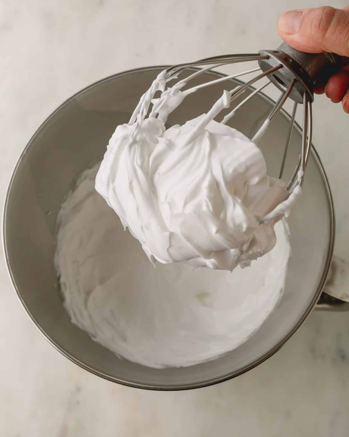 White meringue at stiff peak stage balled up inside a whisk.